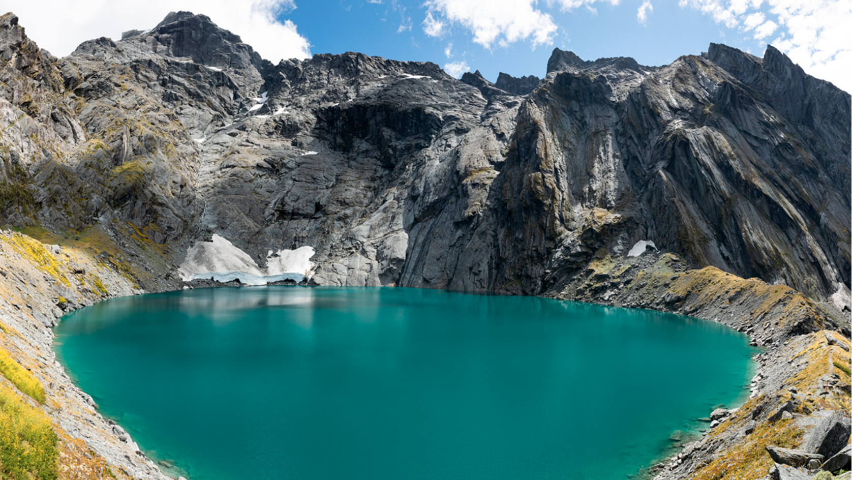 Traveller standing at the base of a lush New Zealand waterfall, highlighting NZ’s free and accessible nature experiences.